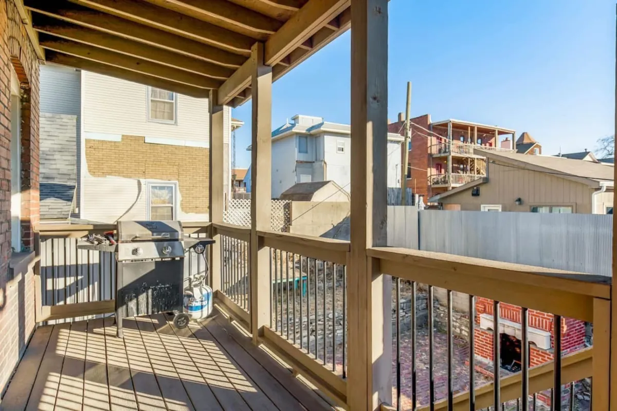 This image features a grill and balcony railing with a backdrop of surrounding buildings, highlighting the friendly and communal outdoor space perfect for post-event barbecues or casual gatherings.