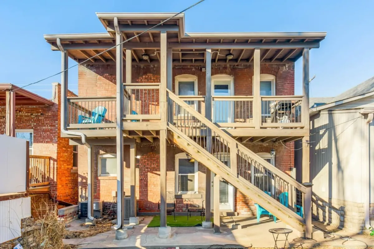 The photo shows two balconies with adirondack chairs and a wooden staircase, emphasizing outdoor relaxation and social gathering. The setup invites guests to unwind after big games or concerts and enjoy sunsets or conversations with friends.