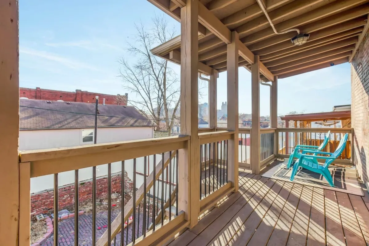 This exterior shot features blue Adirondack chairs arranged on a wooden-railed patio against a backdrop of exposed brick. The scene is tranquil and invites guests to enjoy morning coffee or unwind during breezy afternoons while overlooking the surrounding area.